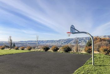 A basketball hoop in a sports court on a grassy hill with mountains in the background.at Canyon View, Idaho, 83501.